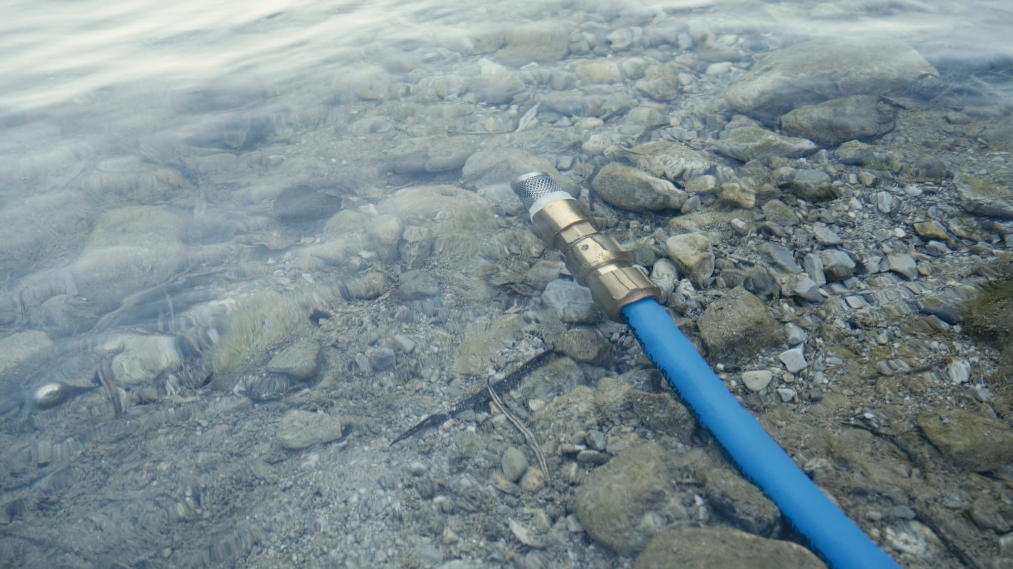 Image of a river with a hose for pumping water using a mesh filter